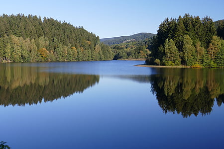 landscape photo of lake near green trees under blue sky during daytime thumbnail
