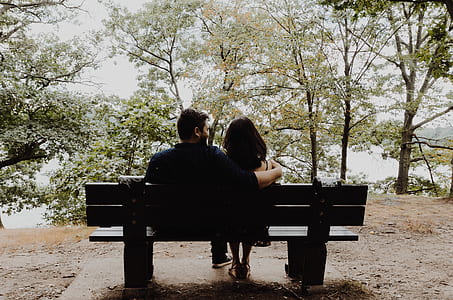 couples sitting on bench in front of green trees and body of water thumbnail