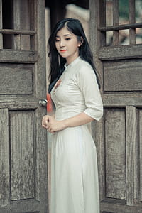 Woman Wearing White Dress in Middle of Two Brown Wooden Doors thumbnail