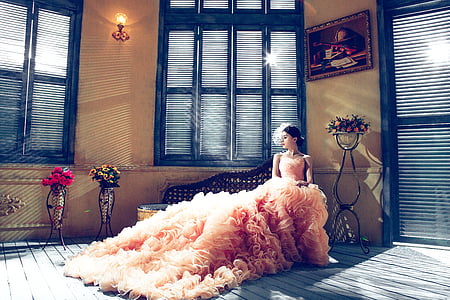 woman wearing pink gown sitting beside window thumbnail