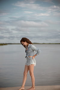 Woman Wearing Gray Denim Tie-front Long-sleeved Shirt and Short Shorts Walking on Isle Near Body of Water thumbnail