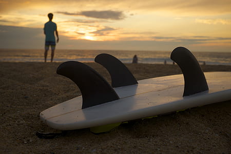 white and black surfboard on sand near seashore at golden hour thumbnail