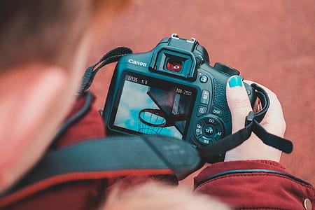 shallow focus photography of black Canon DSLR camera being held by a person thumbnail
