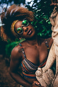 shallow focus photography of woman wearing multicolored bikini top behind the green leafed plants thumbnail