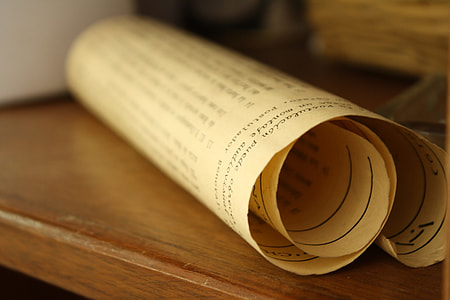 white scroll of paper on brown wooden surface thumbnail