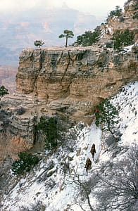 View of snow covered rim of the Grand Canyon in Arizona. Mule riders passing through rock tunnel on near the start of the Bright Angel Trail, headed into the Canyon. thumbnail
