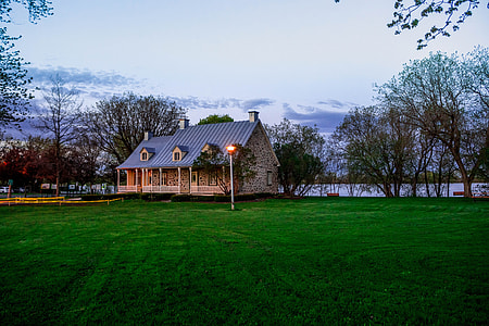 house near river beside trees under calm sky thumbnail