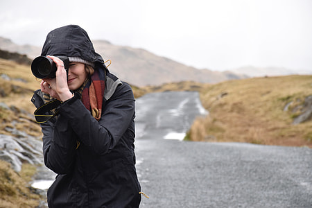 woman holding camera standing on gray concrete road at day time thumbnail