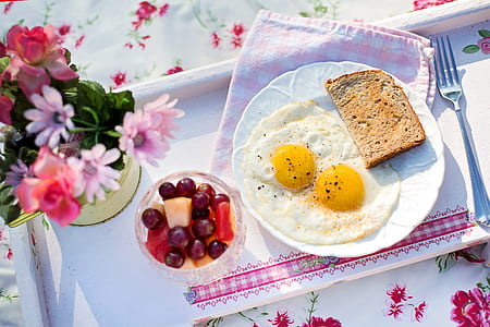 fried egg and sliced bread on plate beside cup of fruits thumbnail