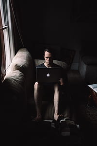 man sitting on grey couch using MacBook thumbnail