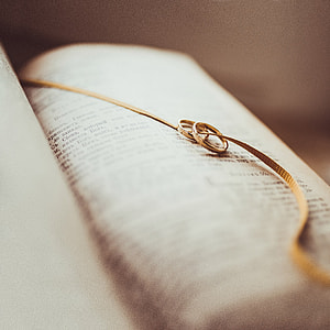 two gold-colored rings with necklace placed on top of book thumbnail