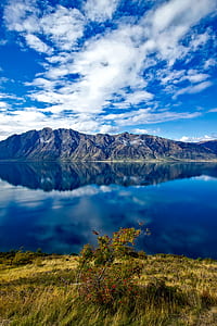 reflective photography of mountain on body of water thumbnail