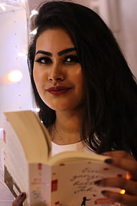 Black Haired Smiling Woman Holding Book thumbnail