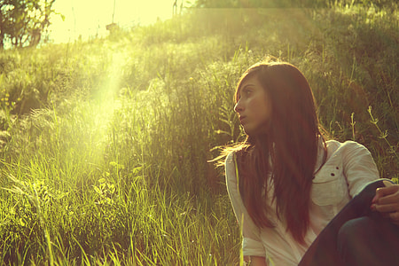 brown haired woman sitting on green grass fields thumbnail
