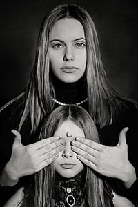 grayscale photography of adult woman covering eyes of young girl using her hands thumbnail