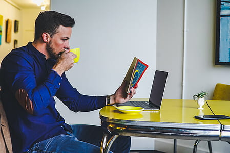 man holding cup and reading book thumbnail