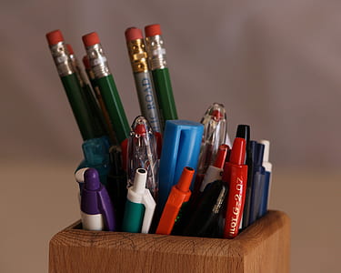 assorted-color pencil and pens on brown wooden pen rack thumbnail