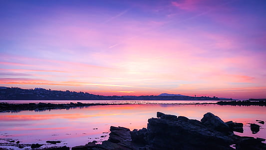 calm body of water near mountain at daytime thumbnail