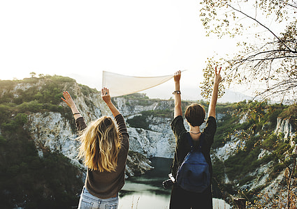 boy and girl raising their two hands in front of rock formation during daytime thumbnail