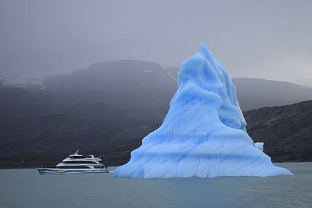 iceberg beside yacht at daytime thumbnail