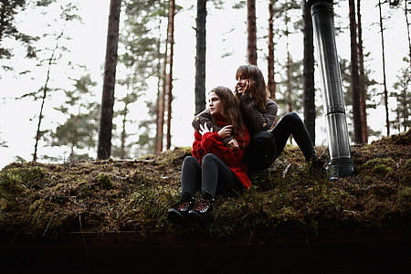 Two Woman Sitting on Brown and Green Grass Outdoors thumbnail