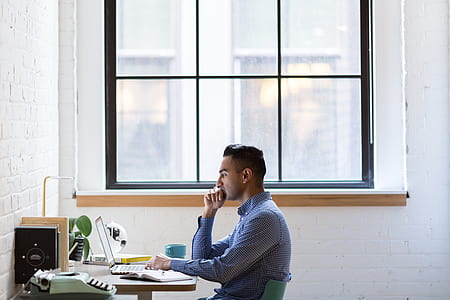 man wearing blue dress shirt sitting on green chair thumbnail