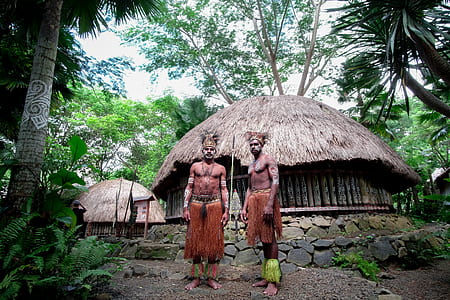 two man near two brown nipa huts surrounded by trees at daytime thumbnail