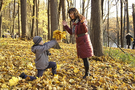boy holding flowers kneel in front of woman in middle of trees thumbnail