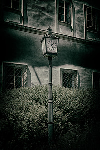 grayscale photography of outdoor post lamp with clock near house thumbnail