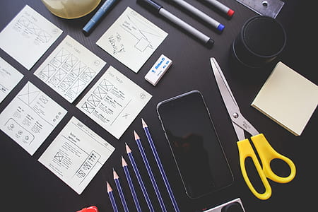 space gray iPhone 6 beside scissors, pencils, and printed paper on black table thumbnail