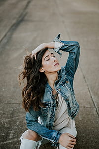 woman wearing denim jacket sitting on concrete pavement thumbnail
