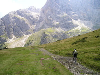 man in black jacket with backpack riding mountain bike climbing mountain trails during daytime thumbnail