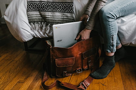 person putting acer laptop on brown leather satchel bag thumbnail