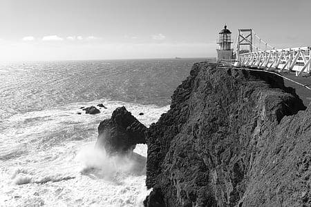 lighthouse on mountain cliff near body of water thumbnail