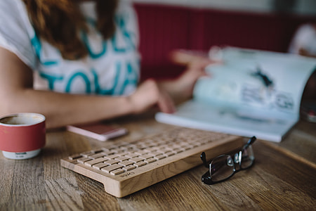 Closeup of female hands typing text on a wireless wooden keyboard thumbnail