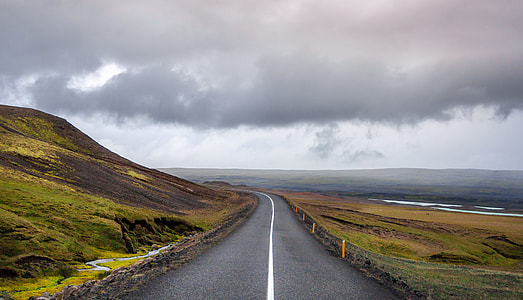 empty gray concrete road top surrounded with green grass near shore during daytime thumbnail