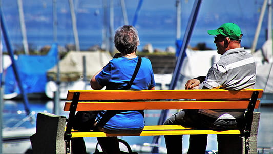 man and woman sitting on bench outdoors by day thumbnail