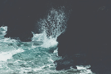 ocean water crashing on black rock wall formation thumbnail