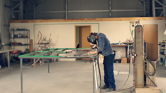 person in black welding mask near green table thumbnail