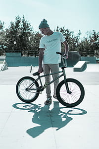 man wearing white Calvin Klein crew-neck t-shirt holding gray BMX bike thumbnail