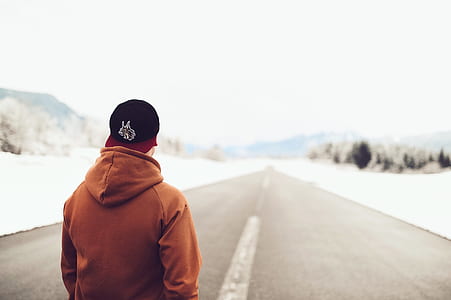 Person in Brown Hoodie Standing on Asphalt Road thumbnail