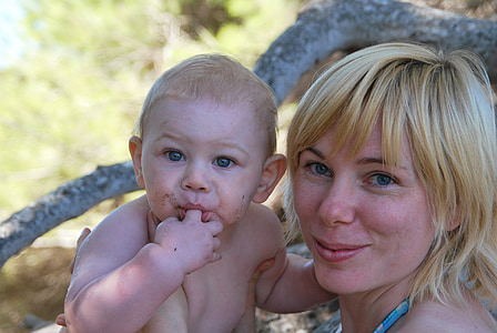 woman carrying child near tree thumbnail
