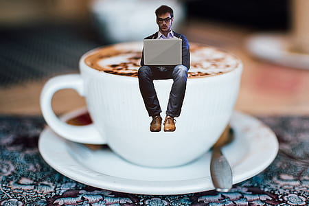 man in blue jacket using laptop above white teacup with saucer thumbnail