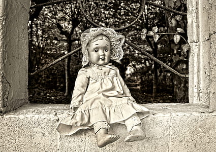 girl doll sitting on concrete pavement thumbnail