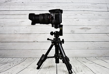 black DSLR camera beside tripod thumbnail