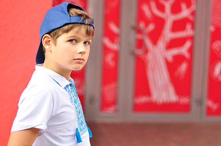 boy wearing blue fitted cap backwards near red wall thumbnail