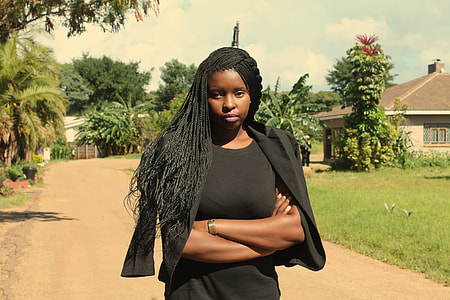 woman wearing black blazer walks near tree during daytime thumbnail
