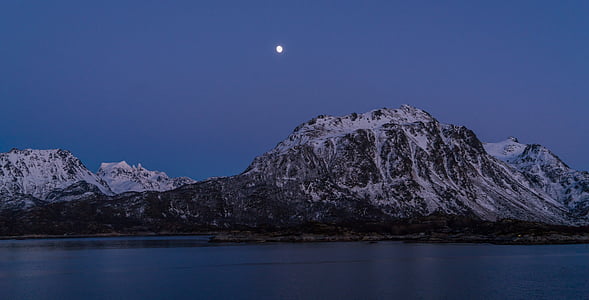 mountain coated with snow beside body of water thumbnail