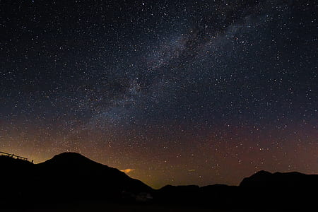 silhouette of mountain under sky and stars at night time thumbnail