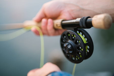 shallow focus photography of a person holding brown fishing rod thumbnail